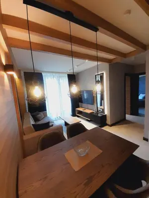 a living room with a table and a living room with a couch at Woodside RENT Kopaonik in Kopaonik