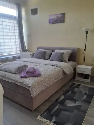 a bedroom with a large bed with purple towels on it at Apartman Leggiero in Vrnjačka Banja