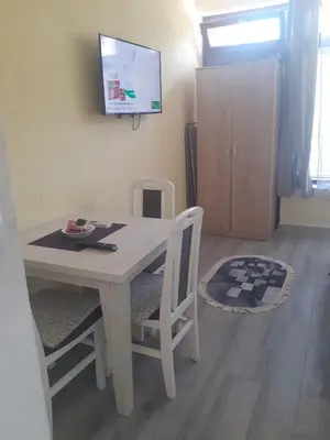 a white dining room table with two chairs and a tv at Apartman Leggiero in Vrnjačka Banja