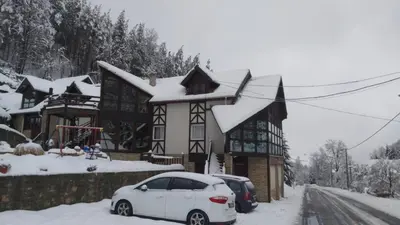 a white car parked in front of a house with snow at Ski hotel DOBRODOLAC in Kopaonik
