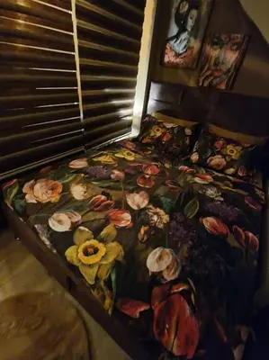 a bed with a floral bedspread with flowers on it at Supreme studio in Niš