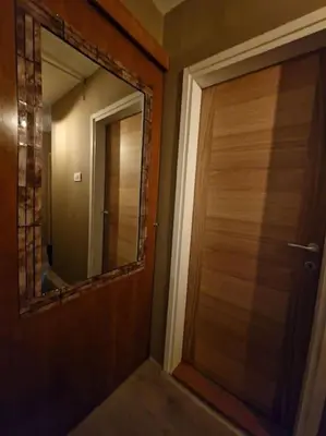 a bathroom with a wooden door and a mirror at Supreme studio in Niš