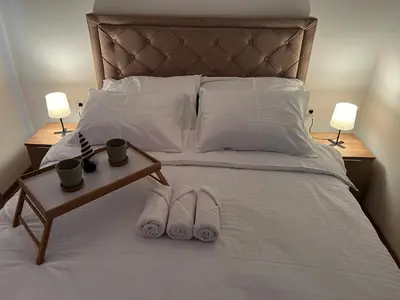 two pairs of slippers on a bed with two lamps at Apartments SKY Kopaonik in Kopaonik