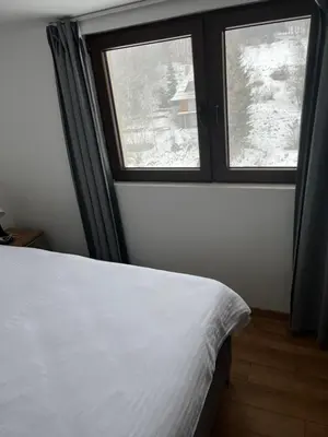a bedroom with a white bed and two windows at Apartments SKY Kopaonik in Kopaonik