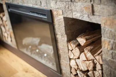 a stone fireplace with a pile of wood in it at Vidik Dream Kopaonik in Kopaonik