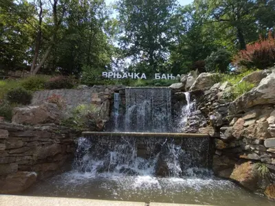 a waterfall in a stone wall in a garden at Apartman Rajčić in Vrnjačka Banja