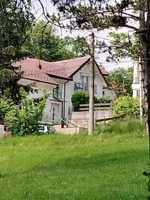 a white house with a red roof and a yard at Apartman Rajčić in Vrnjačka Banja
