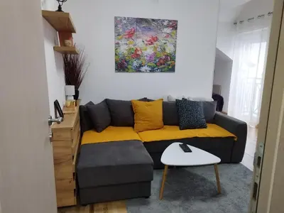 a living room with a couch with a yellow blanket at Apartman Rajčić in Vrnjačka Banja