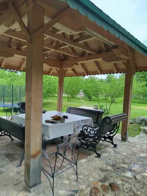 a table and chairs under a wooden pavilion at GOČ Planinska Kuća MILJA in Kraljevo