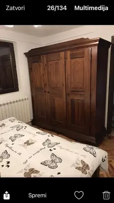 a bedroom with a bed and a wooden cabinet at GOČ Planinska Kuća MILJA in Kraljevo