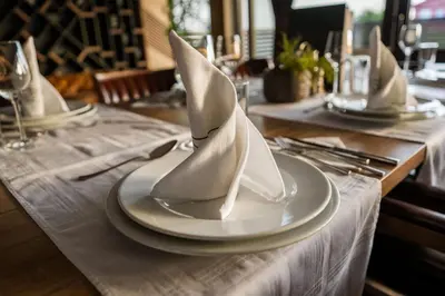 a table set with white plates and napkins with white napkinwered at Hotel & Restaurant Ponte Bianco in Vranje