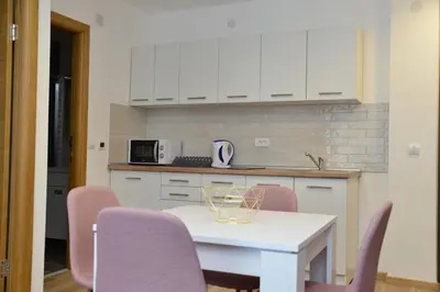 a kitchen with a white table and pink chairs at Kraljevi Cardaci Cardak in Kopaonik