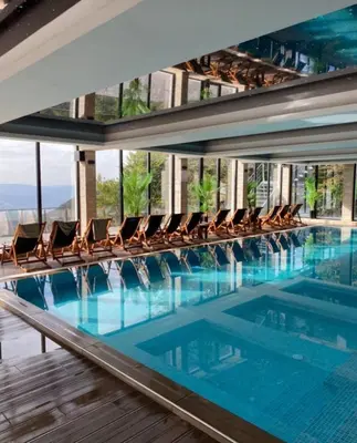 a swimming pool with chairs in a building at Apartmani L6 & P90 Milmari Kopaonik in Kopaonik