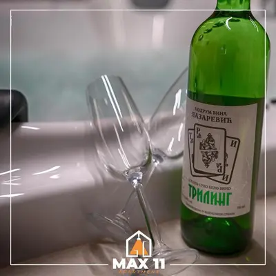 a green bottle of wine next to a wine glass at MAX 11 Apartman in Kruševac