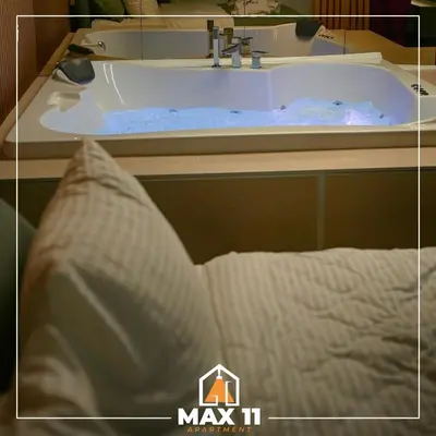 a bath tub with a pillow in front of a sink at MAX 11 Apartman in Kruševac