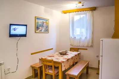 a small dining room with a table and a refrigerator at Vila Milica Apartmani in Kopaonik