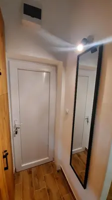 a mirror on a wall next to a door at Apartman GreenPine in Soko Banja