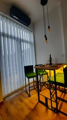 a dining room with a table and chairs and a large window at Apartman GreenPine in Soko Banja