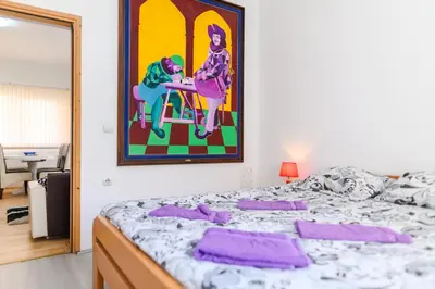 a bedroom with a bed with purple pillows on it at Apartmani Merlin in Soko Banja