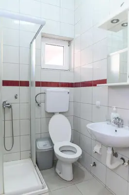 a white bathroom with a toilet and a sink at Apartmani Merlin in Soko Banja