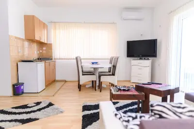 a living room with a kitchen and a table with chairs at Apartmani Merlin in Soko Banja