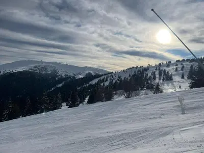 a snow covered slope with the sun on a mountain at WEGA Star Apartmani in Brzeće
