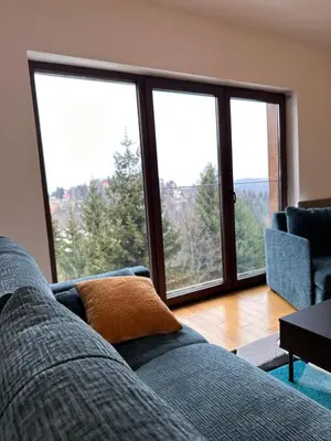 a living room with a couch and large windows at Glecer A07 in Kopaonik