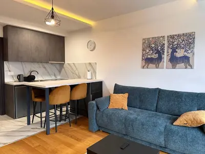 a living room with a blue couch and a kitchen at Glecer A07 in Kopaonik