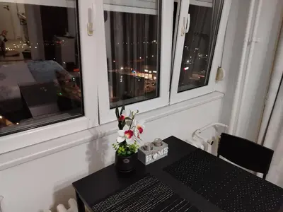 a table with flowers on it in a room with windows at Studio apartman Nataly in Kruševac