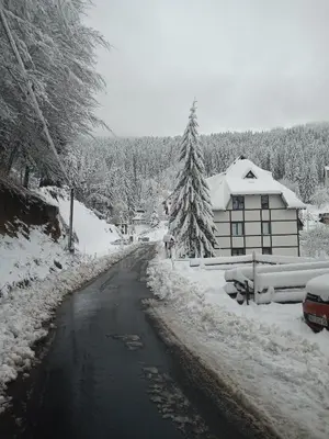 a road covered in snow next to a house at KopanikSkiRooms15E in Kopaonik