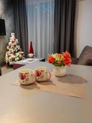 a table with two cups and a vase with flowers at Apartmani MiS apartman br 2 in Soko Banja