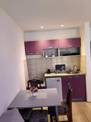 a kitchen with purple cabinets and a table with flowers at Apartmani MiS apartman br 2 in Soko Banja