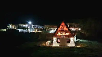 a small house with a red roof at night at KoCHALET Apartment in Crni Vrh