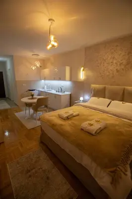 a bedroom with a large bed and a kitchen at Lotos Apartments in Kruševac