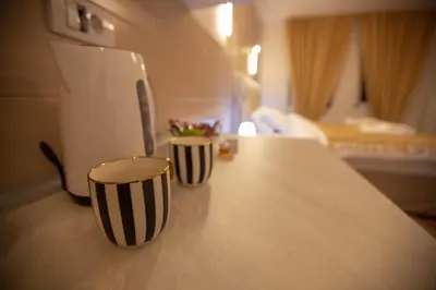 two black and white cups on a counter with a refrigerator at Lotos Apartments in Kruševac