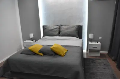 a bedroom with a large bed with two yellow pillows at BeLux apartment in Niš