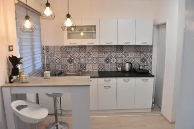 a kitchen with white cabinets and a counter top at BeLux apartment in Niš