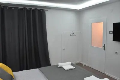 a bedroom with a bed and a black curtain at BeLux apartment in Niš