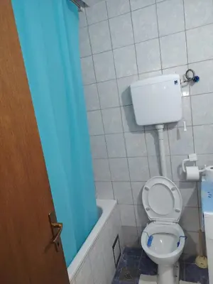a bathroom with a toilet and a blue shower curtain at Fili 1 in Ćuprija