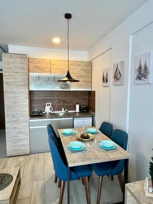 a kitchen with a dining table and blue chairs at ICE-KOP Milmari in Kopaonik