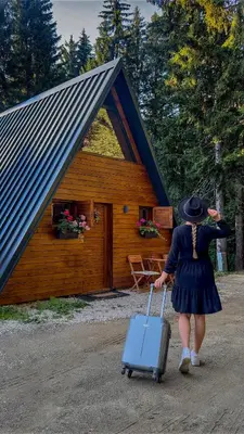 a woman pulling a suitcase in front of a cabin at Viktorija chalet in Kopaonik