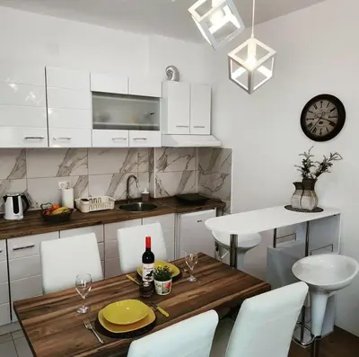 a kitchen with a wooden table and white cabinets at SokoStar Lux in Soko Banja