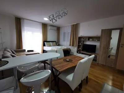 a living room with a table and white chairs at SokoStar Lux in Soko Banja