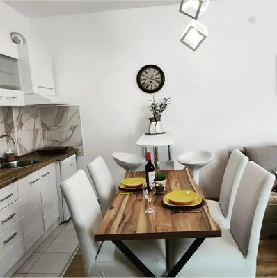 a dining room table with white chairs and a clock on the wall at SokoStar Lux in Soko Banja