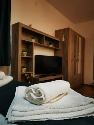 a living room with a television and towels on a bed at SokoStar Lux in Soko Banja