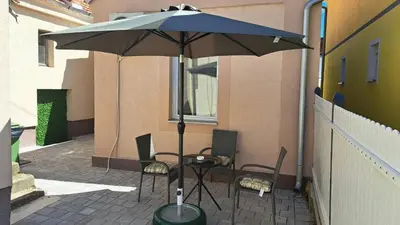 a table and chairs under an umbrella on a patio at Apartman Arsić Zajecar in Zaječar