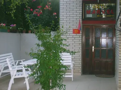 a table and chairs in front of a building with a door at Smeštaj - sobe MARVEL in Niš