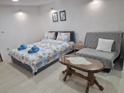 a bedroom with a bed and a chair and a table at Zed Apartments in Leskovac