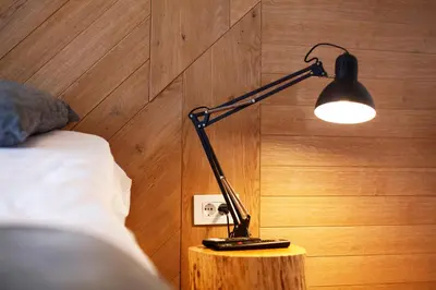 a black lamp sitting on a table next to a bed at UrbanKop Vidik Residence in Kopaonik