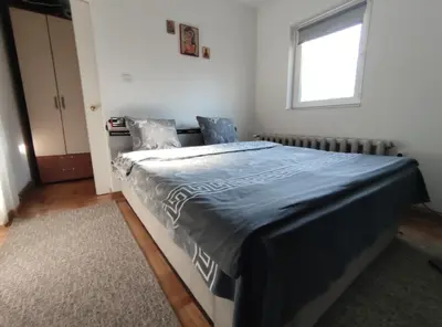 a bedroom with a bed with a blue comforter and a window at Nikolic Apartment in Leskovac